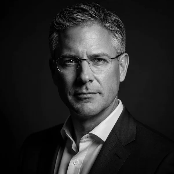 Executive B&W AI headshot example — professional man in his 40s with glasses (AI-generated, not a real person)